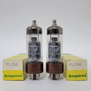 May include: Two Amperex PL36 vacuum tubes with clear glass envelopes and brown bases, each standing upright next to its original yellow and white cardboard box. The tubes feature black internal components and white text reading Amperex 64 32 Made in France PL36.