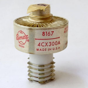 May include: A silver and white Eimac 4CX300A vacuum tube with a red label that reads "Eimac 4CX300A Made in U.S.A." and "8167 06980".