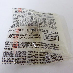 May include: A close-up of a white plastic bag with the text "AMPHENOL CONNECTORS FROM" and "BUNKER RAMO" printed on it. The bag contains a variety of RF connectors and switches. The text "When you can connect it and forget it...that's quality." is also printed on the bag.