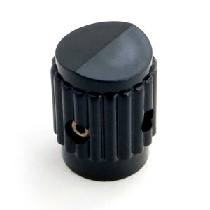 May include: Black plastic knob with a ribbed design and two small holes. The knob has a flat top.