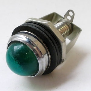May include: A green glass indicator light with a chrome bezel and a metal mounting bracket. The light is mounted on a black rubber grommet.