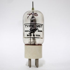 May include: A clear glass vacuum tube with a white ceramic base and four metal pins. The label reads TYPE 25T, Eimac, REG.U.S. PAT.OFF., and MADE IN U.S.A. A thin metal rod extends from the top, and internal metal components are visible inside.