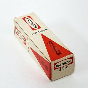 May include: A vintage Raytheon Electronic Tube box. The rectangular box is off-white with red accents and text. The text includes "RAYTHEON", "ELECTRONIC", and "TUBE". The box also has the text "2E36".