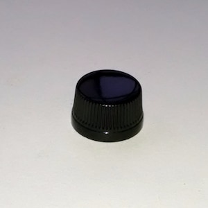 May include: A black plastic bottle cap with a ribbed design.
