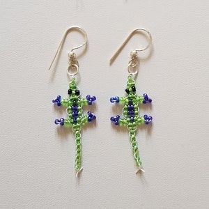 May include: A pair of green beaded lizard earrings with pink accents and a pair of green beaded lizard earrings with blue accents.