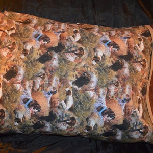 May include: A brown and tan pillowcase with a repeating pattern of hunting dogs and ducks. The pillowcase has a brown border.