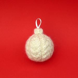 May include: A white knitted Christmas ornament with a white ribbon loop.