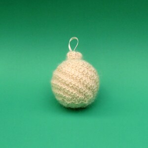 Op de afbeelding: Een witte gebreide kerstbal met een witte lintlus.