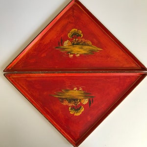 May include: Two red, diamond-shaped trays with a landscape scene. Each tray features a painted island with a house, trees, and water. The trays have a distressed, vintage look with gold trim.
