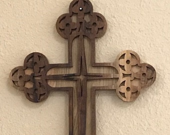 May include: A wooden cross with intricate carvings and a dark brown stain. The cross is made of wood with a natural grain pattern.
