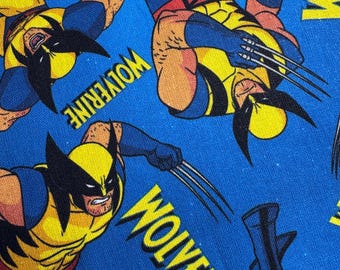 Könnte beinhalten: Blauer Stoff mit einem sich wiederholenden Muster der Marvel Comics-Figur Wolverine. Die Illustration zeigt Wolverine in seinem gelb-blauen Kostüm mit ausgestreckten Krallen. Das Wort "Wolverine" ist ebenfalls auf dem Stoff aufgedruckt.