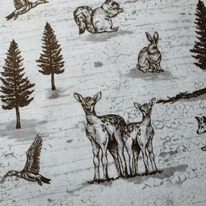 May include: A fabric with a repeating pattern of woodland creatures in shades of brown and gray. The design includes deer, squirrels, rabbits, ducks, and pine trees, set against a textured, light gray background.