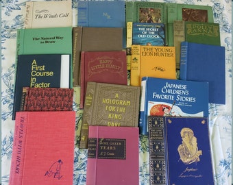 May include: A collection of vintage hardcover books with various titles and authors. The books are arranged in a grid pattern on a white and blue floral tablecloth. Some of the titles include "The Winds Call", "The Natural Way to Draw", "A First Course in Factor", "Happy Little Family", "The Young Lion Hunter", "A Hologram for the King", "Japanese Children's Favorite Stories", "The Love Story of Empress Josephine", and "The Green Years".