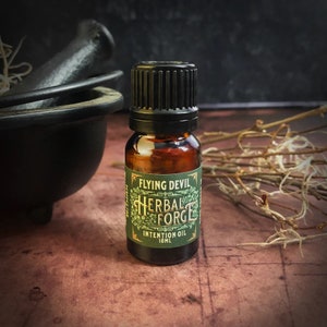 May include: A small brown glass bottle with a black cap and a green label that reads "Flying Devil Herbal Forge Intention Oil 10ml".