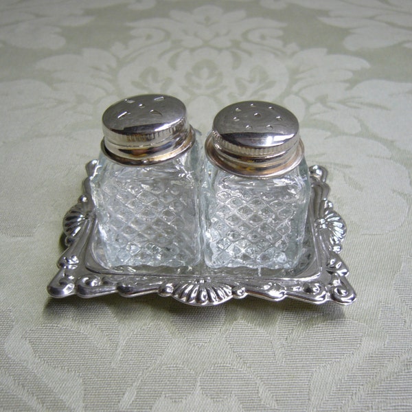 Vintage small pressed glass and chrome plated salt and pepper shakers on a chrome plated tray