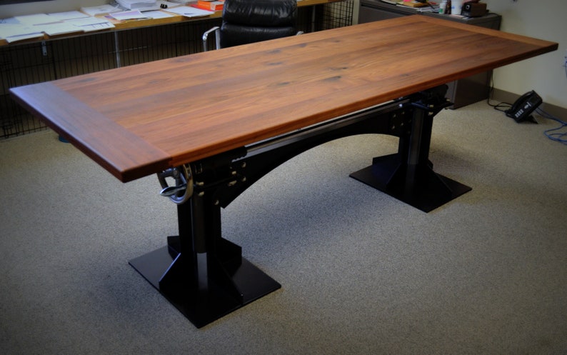 May include: A large wooden table with a dark brown finish and black metal legs. The table has a rectangular top and a unique design with a metal support beam.