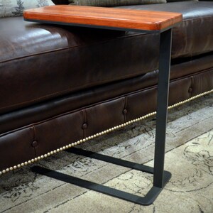May include: A wooden side table with a black metal frame. The table has a rectangular top and a simple design.