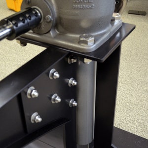 May include: A black metal stand with a silver metal cylinder and a silver metal gear mechanism. The gear mechanism has a black handle and a label that reads "JOYCE 08840882".