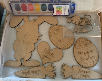 Pode incluir: Um kit de artesanato de madeira para a Páscoa com um coelho, ovos, cenouras e um coração que diz "Eu te amo". O kit inclui oito aquarelas e um pincel.