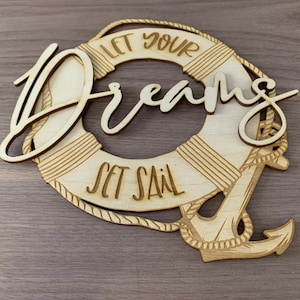 May include: Wooden sign with a life preserver and anchor design. The sign says "Let your dreams set sail".