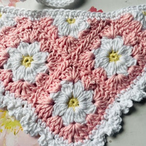 Op de afbeelding: Roze en witte gehaakte granny square met een madeliefjesontwerp. Het vierkant heeft een gegolfde rand.