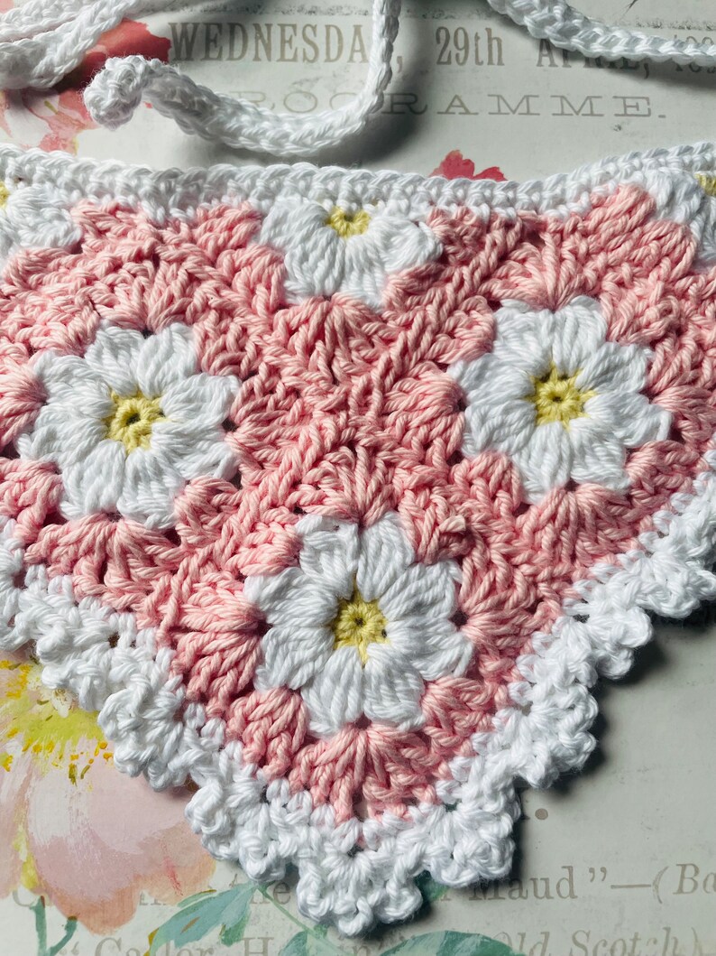 Op de afbeelding: Roze en witte gehaakte granny square met een madeliefjesontwerp. Het vierkant heeft een gegolfde rand.