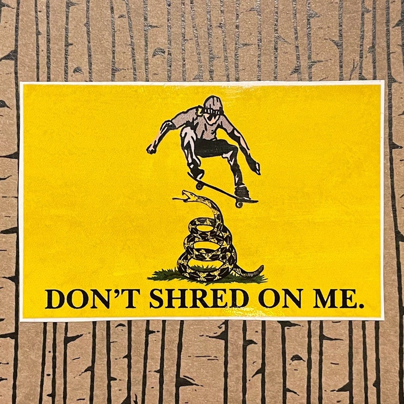 K&ouml;nnte beinhalten: Gelber Aufkleber mit einem Skateboarder, der &uuml;ber einer zusammengerollten Schlange springt. Der Text "DON'T SHRED ON ME" ist in Schwarz gedruckt. Der Skateboarder und die Schlange sind in Schwarzwei&szlig;.