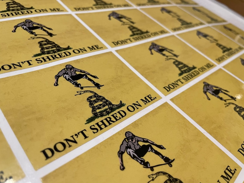 K&ouml;nnte beinhalten: Ein Bogen Aufkleber mit gelbem Hintergrund. Jeder Aufkleber zeigt einen Skater, eine zusammengerollte Schlange und den Text "DON'T SHRED ON ME." Der Skater ist in Bewegung, und die Schlange ist gr&uuml;n und braun. Die Aufkleber sind in einem Raster angeordnet.