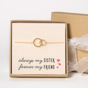 May include: A gold chain bracelet with two interlocking circles. The bracelet is in a box with a card that reads "always my sister, forever my friend" with pink hearts.