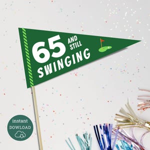 May include: A green pennant flag on a wooden stick with the text "65 AND STILL SWINGING" in white. The flag has a golf-themed design with a golf ball and flag. A small, round, green button with the words "instant DOWLOAD" is in the lower left.