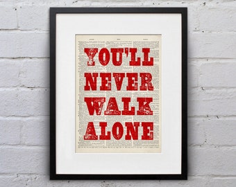 May include: A framed print featuring the words "You'll Never Walk Alone" in red lettering on a vintage newspaper background.