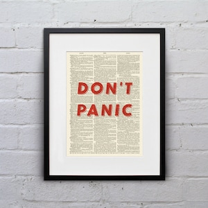 May include: A framed print of a vintage dictionary page with the words "DON'T PANIC" in red lettering.