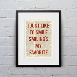 Puede incluir: Una impresión enmarcada con un fondo de página de diccionario vintage. El texto "I JUST LIKE TO SMILE SMILING'S MY FAVORITE" está impreso en rojo.