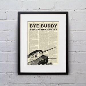 Puede incluir: Impresión artística enmarcada con una ilustración de narval y el texto "BYE BUDDY HOPE YOU FIND YOUR DAD". La obra utiliza una página de diccionario vintage como fondo, presentada en un marco negro y un passe-partout blanco.
