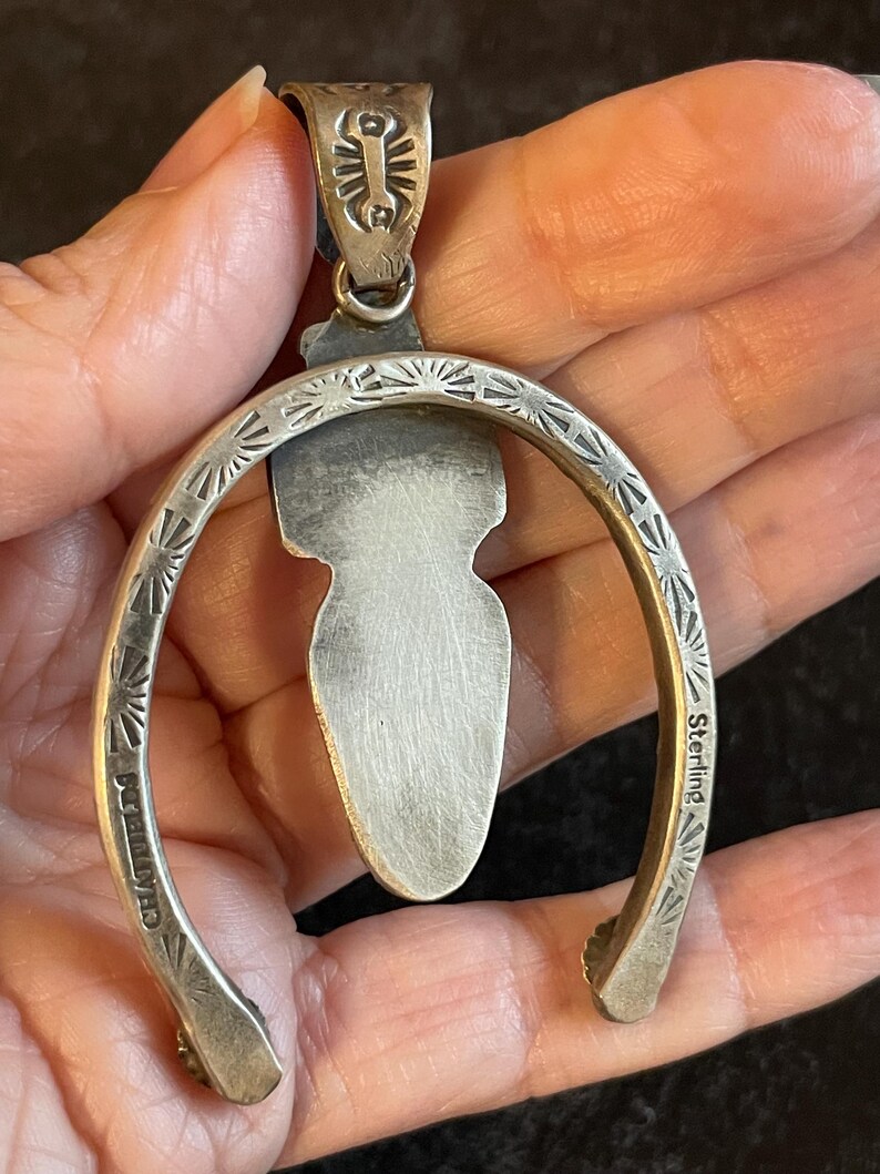 May include: A silver pendant with a horseshoe design. The pendant features a central, elongated stone and is marked "Sterling" and "CHASTFIELD". The horseshoe is decorated with sunburst patterns.