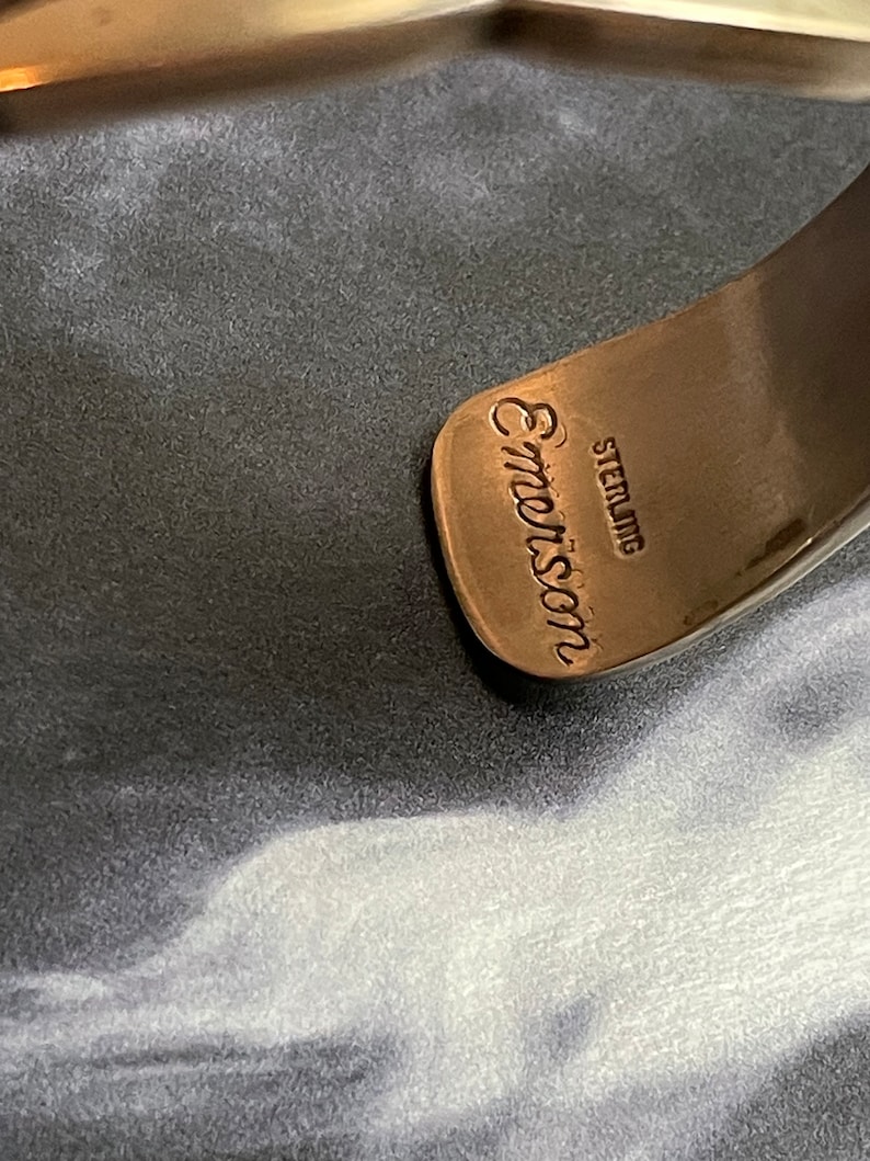 May include: Close-up of a silver bracelet with the inscription "Emmon's Sterling" on the inside.