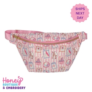 May include: A pink and white fanny pack with a gold zipper and pink strap. The bag features a repeating pattern of framed illustrations and vertical pink stripes. The text "Honey Boutique & Embroidery" is visible.