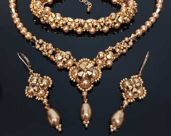 May include: A gold-toned beaded jewelry set with a long necklace, a shorter bracelet, and a pair of dangling earrings. The necklace and bracelet feature a floral design with a central cluster of beads.