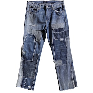 May include: Blue denim jeans with a patchwork design. The jeans feature various shades of blue denim patches sewn together, creating a unique and distressed look. The jeans have a classic five-pocket design and a straight leg.
