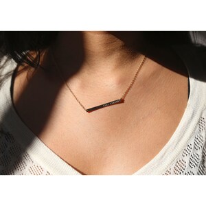 May include: A gold necklace with a thin chain and a bar pendant that says "STAY STRONG".