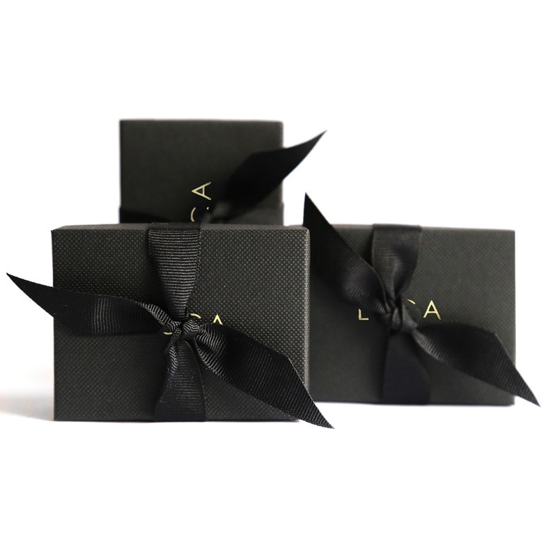May include: Three black gift boxes with black ribbon bows and gold lettering that says "LCA" on each box.