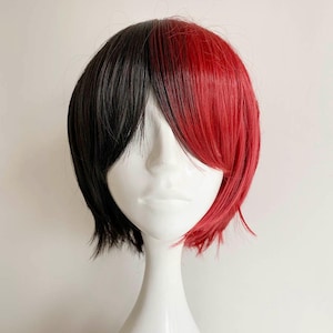 May include: A two-toned wig with a short, layered style. The wig is split down the middle, with one side black and the other vibrant red. The wig is displayed on a white mannequin head.