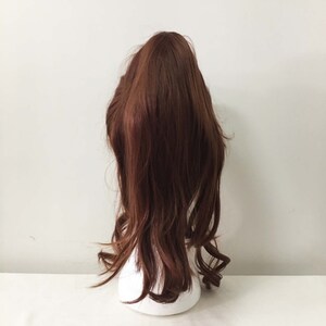 K&ouml;nnte beinhalten: Eine lange, braune, gewellte Pferdeschwanz-Haarverl&auml;ngerung. Das Haar ist locker und l&auml;ssig gestylt, mit einigen Str&auml;hnen, die um das Gesicht fallen.