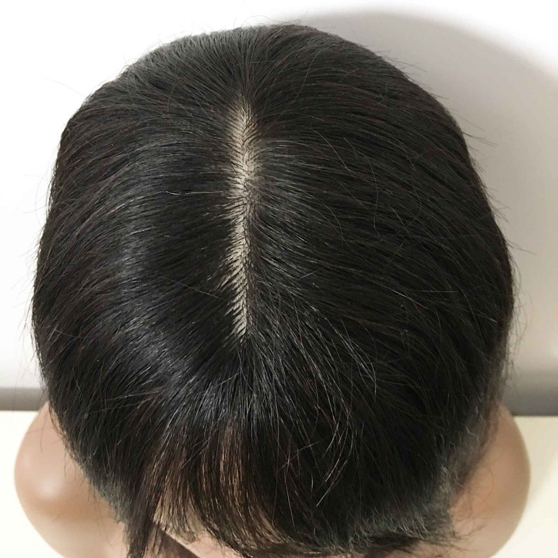 May include: A black wig with a center part. The wig is made of human hair and has a natural look.