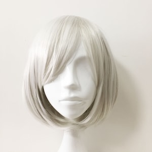 May include: A short, straight, platinum blonde wig with a side part. The wig is on a white mannequin head.