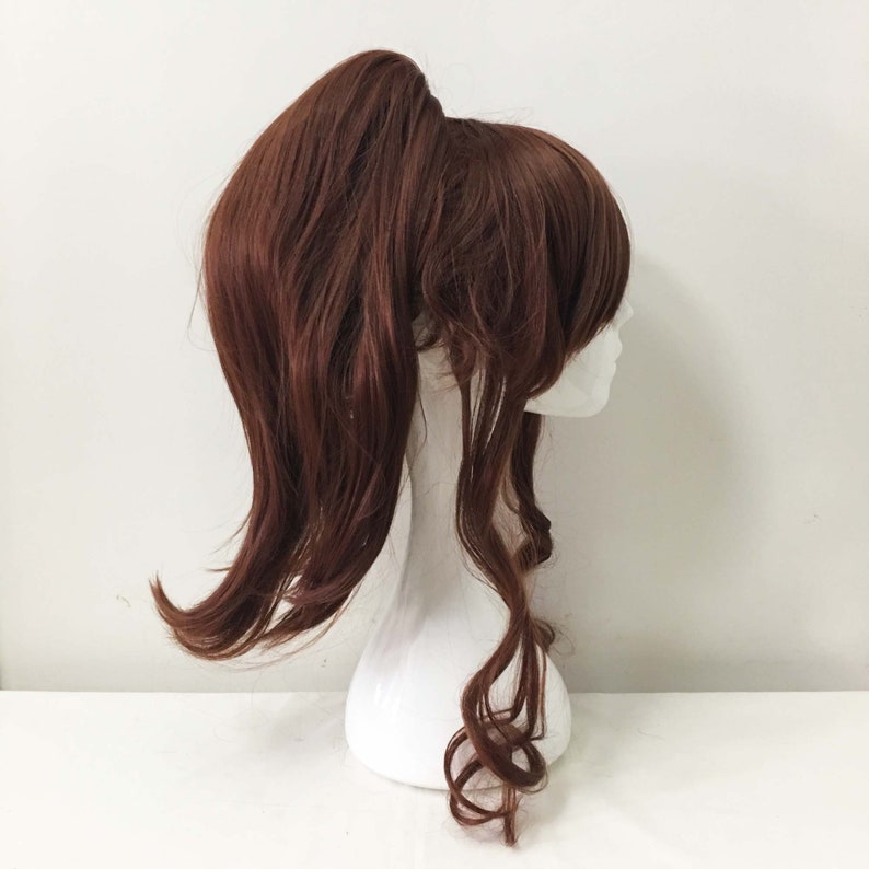 K&ouml;nnte beinhalten: Eine lange, braune Per&uuml;cke mit einem hohen Pferdeschwanz und lockeren Locken. Die Per&uuml;cke ist auf einem wei&szlig;en Mannequin-Kopf gestylt.