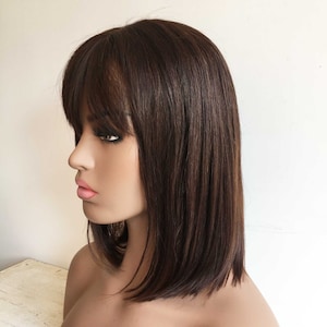 May include: A brown bob wig with bangs. The wig is styled with straight hair and has a natural-looking finish.
