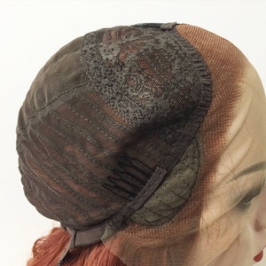 May include: The underside of a brown wig cap with adjustable straps and clips. The cap is made of a fine mesh material.