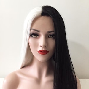 May include: A long, straight wig with half black and half white hair. The wig is styled with a center part and the hair is parted down the middle of the head.