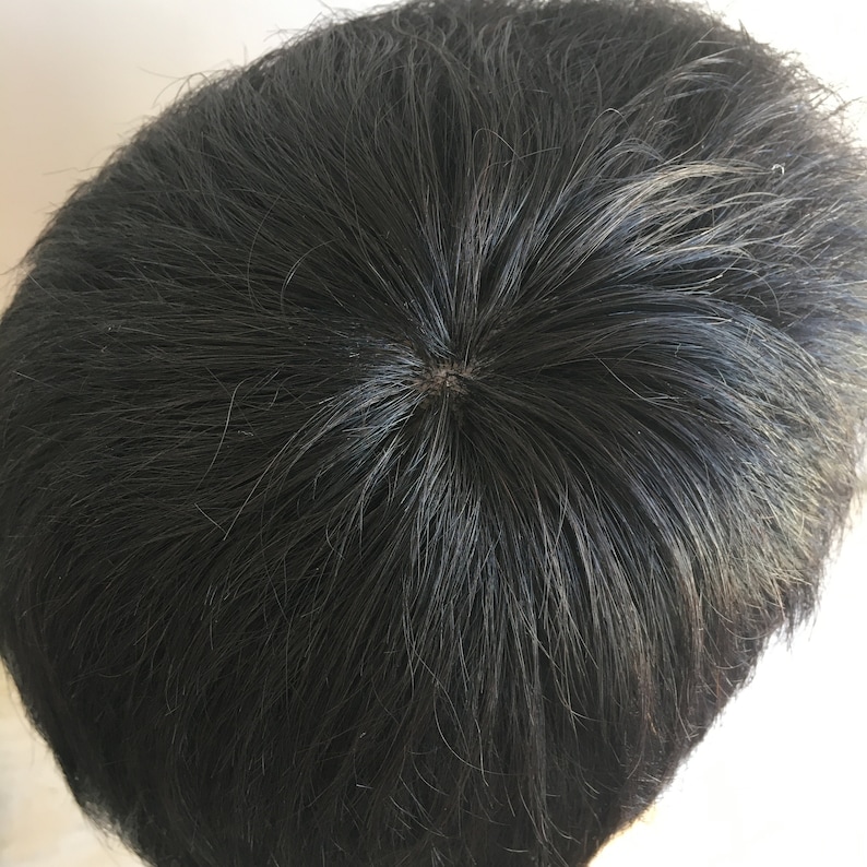 May include: A black toupee with a circular opening in the centre, designed to cover hair loss.